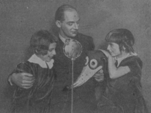 Photographie en noir et blanc du dessinateur entouré de deux jeunes filles.