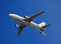 Photo d'un avion blanc dans le ciel avec une nacelle de ravitaillement.