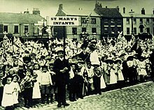 Group of children lined up, holding union flags.