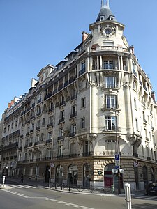 Photo en couleur de l’angle d'une avenue formé par un bâtiment de style haussmannien