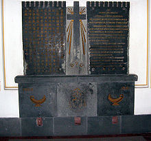 Two dark granite slabs separated by a light granite bas relief cross; Chinese writing on the left slab and the Latin translation on the right slab.