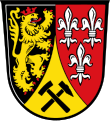 Landkreis Amberg-Sulzbach „Durch eine eingeschweifte, gesenkte goldene Spitze, darin schräg gekreuzt ein schwarzer Schlägel und ein schwarzer Hammer, gespalten von Schwarz und Rot; vorne ein linksgewendeter, rot gekrönter und rot bewehrter goldener Löwe, hinten drei, zwei zu eins gestellte, silberne Lilien.“[1]