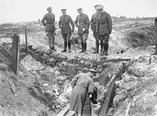 Cinq hommes en uniformes sur le parapet d'une tranchée