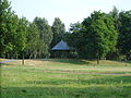 Schutzhütte im Park. Im Hintergrund sind Spielgeräte des Spielplatzes zu erkennen.