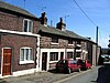 A row of three low cottages in sandstone with painted stone window surrounds