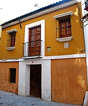 Façade de maison à un étage, vue de 3/4, ocre avec encadrement de porte blanc