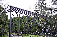 Black wrought iron railing with musical notes and a cannon in the background