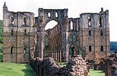 Photographie montrant les ruines d'une vaste église gothique, dont les pierres changent de couleur au-dessus du deuxième niveau d'arcade.