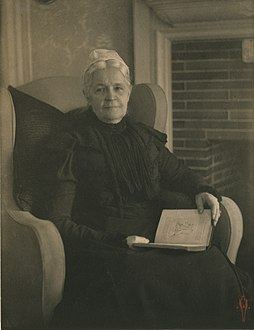 Old woman in an armchair, with an open book in her lap, ca. 1900