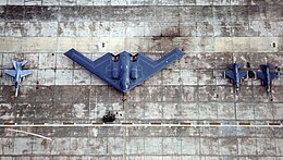 Vue de dessus d'un B-2, stationné entre un F-18 et deux F-16.