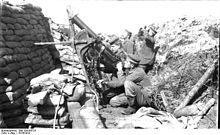 Němečtí vojáci v zákopu obsluhující kulomet pozorují oblohu.