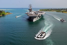 Marineros e infantes de marina formados en la cubierta del USS Ronald Reagan (CVN 76) mientras este se acerca a Pearl Harbor en Hawái, el 28 de junio de 2010, para participar en los 22do ejercicios RIMPAC (en inglés: Rim of the Pacific, en castellano: Costas del Pacífico).