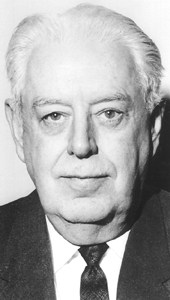 Black and white of a late-middle-aged man with white hair, wearing a dark suit jacket, dark necktie, and white dress shirt