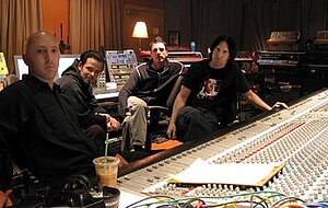 Four men sitting around a large mixing board