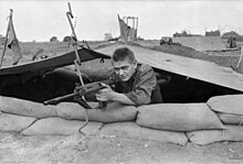 A black and white image of an Australian soldier with an Self Loading Rifle in a defensive position at Fire Support Base Andersen