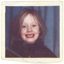 A polaroid of Adele as a child, smiling, with a few missing front teeth