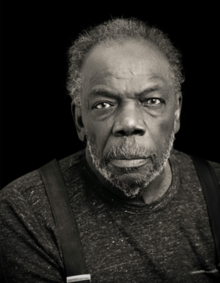 Black man with mustache and beard looking directly into the camera