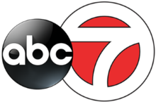 A white 7 in a white circle with red fill, trimmed in black. The ABC network logo, a black disk with lowercase letters a b c, overlaps it on the left side.