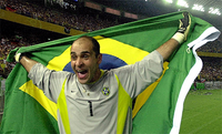 Um homem com feição de alegria, com os braços abertos segurando a bandeira brasileira às suas costas.