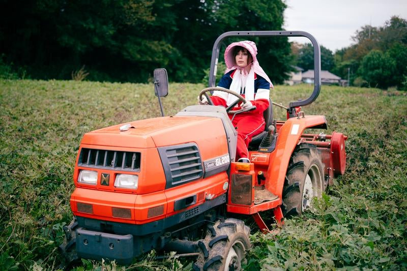 さつまいも畑でトラクターを運転するアメリカ人ハーフの女性の写真