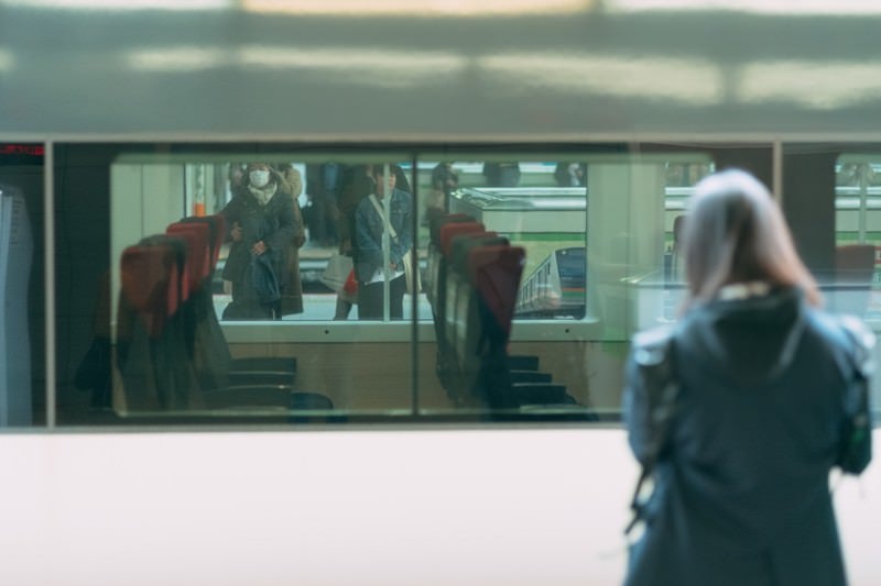 停車中の電車越しに見る利用客の写真