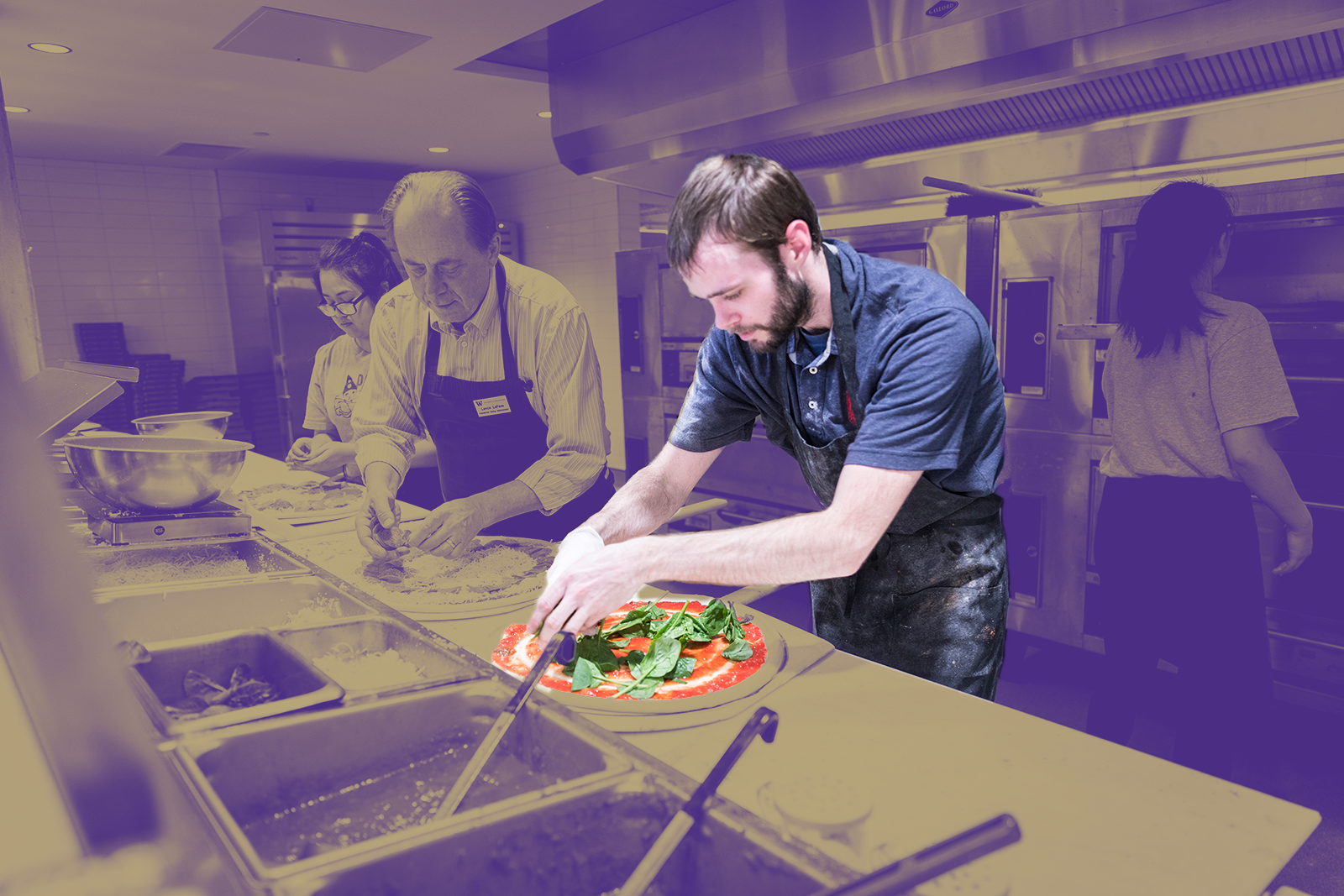 A kitchen employee prepares a pizza for cooking