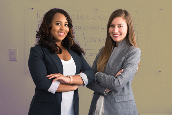 Two smiling female professionals pose for a photograph