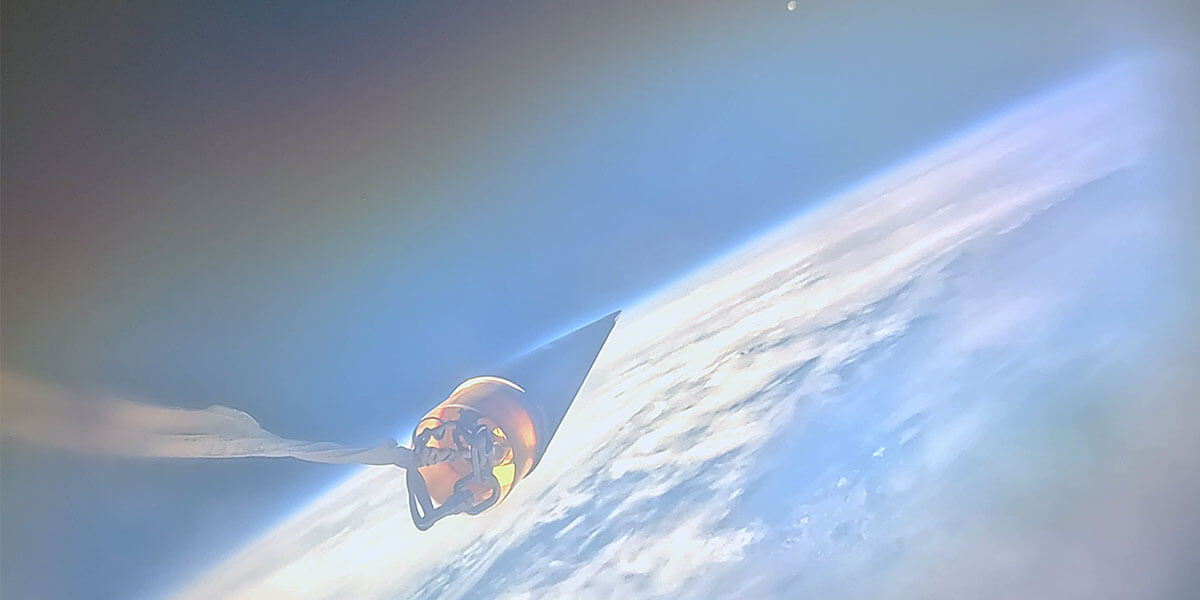 Photo from space. The nose cone of USCRPL's rocket points towards the moon, across Earth's horizon