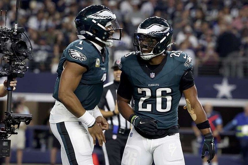 Philadelphia Eagles' Jalen Hurts, left, and Saquon Barkley (26) celebrate after Hurts ran the ball for a touchdown in the second half of an NFL football game in Arlington, Texas, Sunday, Nov. 10, 2024. (AP Photo/Gareth Patterson)