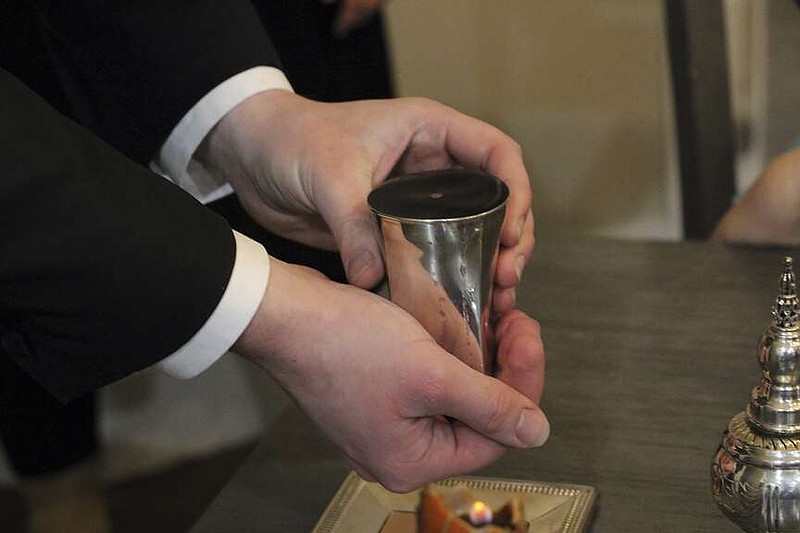 Rabbi Chaim Zippel holds an overflowing cup of wine during a Havdalah service marking the end of the sabbath, Saturday, Nov. 16, 2024, at his home in Lehi, Utah. (AP Photo/Hannah Schoenbaum)