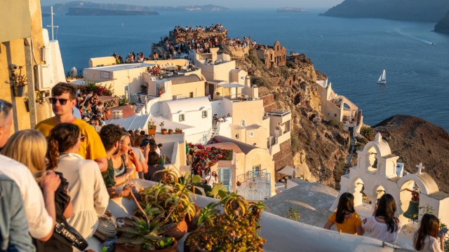 Article thumbnail: Travellers enjoying every bit of free space to admire the sunset at Oia on the island of Santorini, 30 June 2024. With the uncontested growth in the number of visitors to the island of Santorini, the authorities are beginning to think about imposing certain limits on the number of travellers. (Photo by Xavier Duvot / Hans Lucas / Hans Lucas via AFP) (Photo by XAVIER DUVOT/Hans Lucas/AFP via Getty Images)