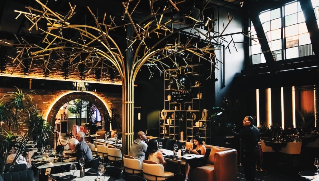 The dimly lit dining room of V's Paradise, with a large golden tree sculpture