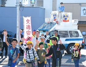 手を挙げて横断歩道を渡る小学生たち