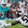 Miami Dolphins running back Chris Brooks (33) tries to escape from Atlanta Falcons linebacker DeAngelo Malone (51) in the second half of a preseason NFL football game, Friday, Aug. 11, 2023, in Miami Gardens, Fla. (AP Photo/Wilfredo Lee)