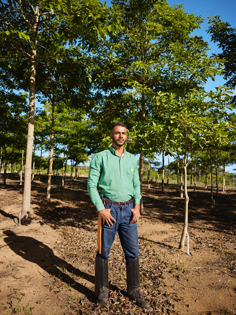 Victor Leon Rocha Araújo 穿著及膝靴站在大西洋沿岸森林的一排樹叢間。