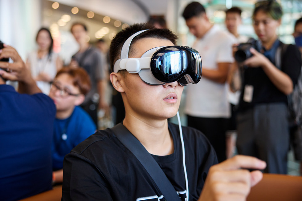 A customer wearing Apple Vision Pro pinches his fingers together.