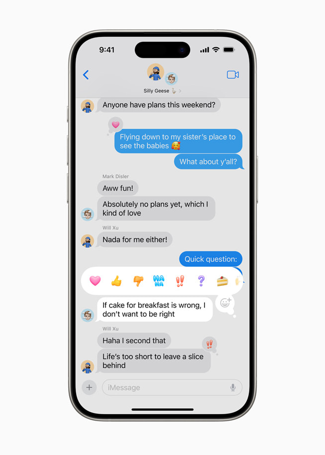 O iPhone 15 Pro mostra uma mensagem selecionada com opções de Tapback, como emoji de coração, polegar para cima, polegar para baixo, haha, ponto de exclamação, ponto de interrogação e bolo.