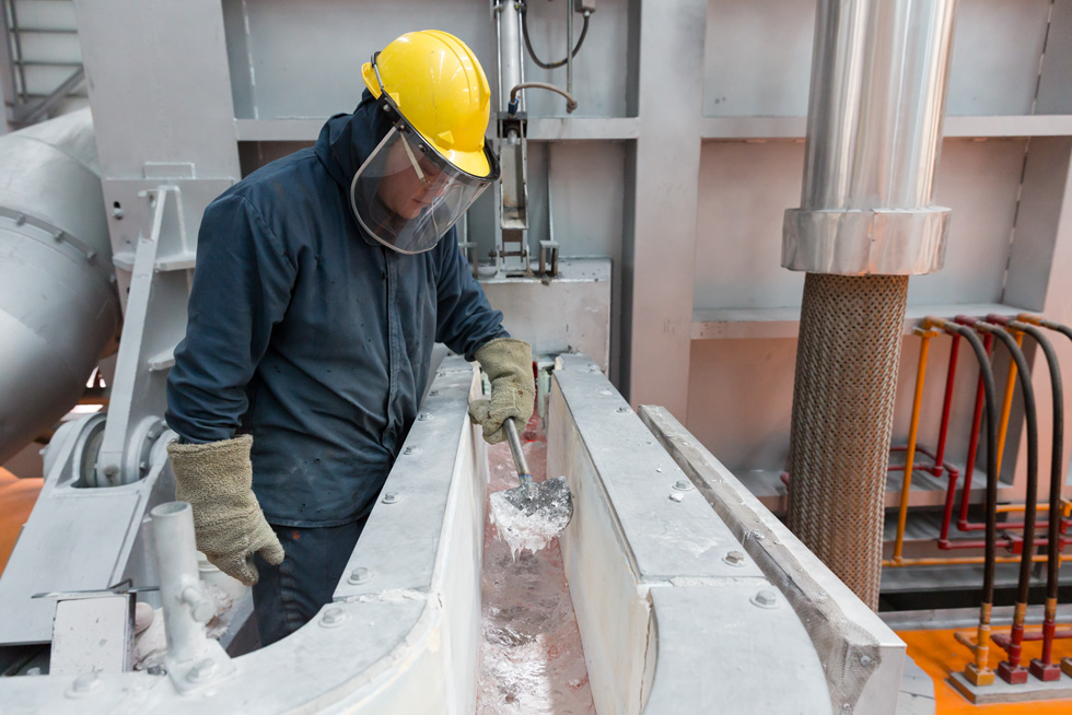 Ein Fabrikarbeiter überwacht den Schmelzprozess in einem Aluminiumwerk.