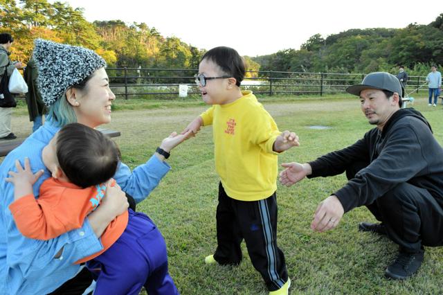 神山春花さん（左）に手を差し出す長男（中央）。週末に家族でよく訪れる公園で=2024年11月3日、仙台市、工藤さほ撮影