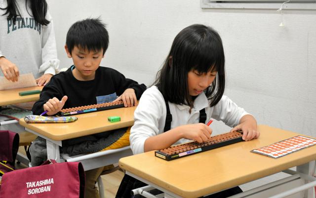 真剣な表情でそろばんの練習をする小学1年生の児童=2024年12月19日午後4時3分、東京都北区の高島珠算学校、石平道典撮影