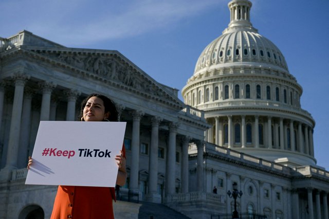 ワシントンで2024年12月、米連邦議会議事堂の外でTikTokを規制する法律に反対してプラカードを持つ人=ロイター