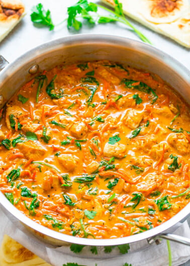 A skillet with creamy tomato spinach pasta sauce, garnished with fresh herbs.