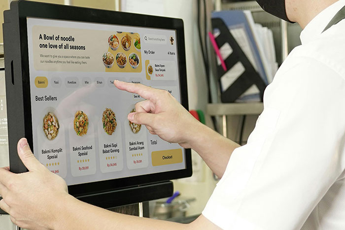 Staff member using a touch screen to manage customer orders in a restaurant.