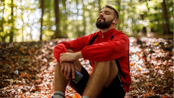 Mann sitzt entspannt und hört Musik. Ablenkung hilft kurzfristig gegen negative Gedanken.  | Bild: wochit/getty images dynamic