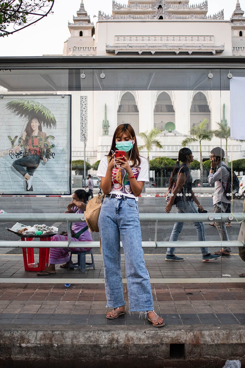 Woman in face mask uses mobile phone in Yangon, Myanmar, in 2020. China has provided substantial COVID-19-related aid to Myanmar.