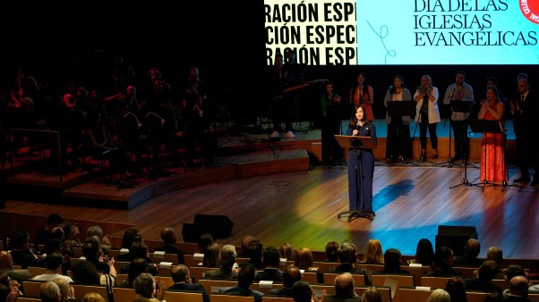 A woman speaking to a crowded room about Argentina's evangelical church day.