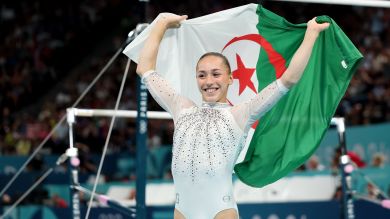 Kaylia Nemour comemora a medalha de ouro nas barras assimétricas com a bandeira da Argélia