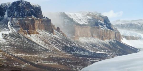 Banded cliffs rise above barren slopes and a large glacier in the dry valleys of Antarctica.  The region forms the coldest, driest, and windiest ecosystems known. (Credit: Michael Gooseff/CU Boulder)