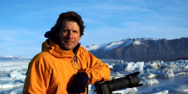 James Balog, founder and director of the Extreme Ice Survey and the Earth Vision Institute, leans on his camera while photographing ice in the field at Jökulsárlón, Iceland. — Credit: Svavar Jónatansson, Extreme Ice Survey