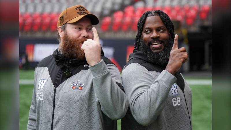 Winnipeg Blue Bombers offensive linemen Patrick Neufeld, left, and Stanley Bryant stand back-to-back while filming a social media video ahead of the 111th CFL Grey Cup, in Vancouver, on Nov. 15, 2024. (Darryl Dyck/The Canadian Press)